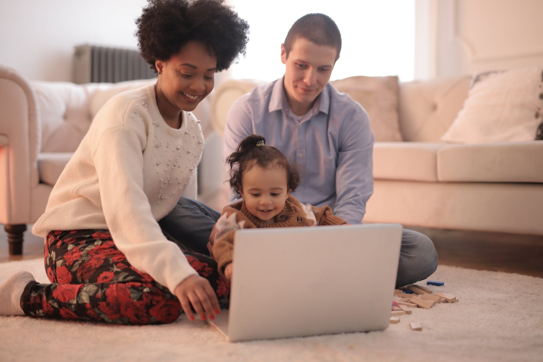 família no chão da sala assistindo a um filme no computador